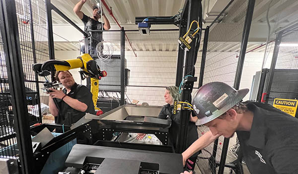 Working with a FANUC robot and a Pregis automated bagging machine, OSARO staff members collaborate with NPSG Global technicians to construct OSARO Robotic Bagging System cells at Zenni Optical in Novato, Calif. 