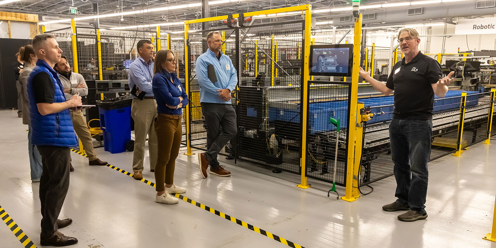 At the next stop on the tour, TA explains BG’s Robotic Shuttle Product Sortation (RSPS) system.

 

Photo by Donald Halsing | Peerless Media