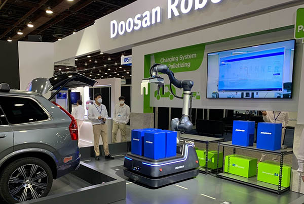 ​Doosan Robotics’ booth had a range of applications. One of the most notable was its mobile manipulator unloading the back of the van.

 A heavy duty robot arm was placed on top of a custom-made automated guided vehicle. A gripper from OnRobot was used to pick up the packages. 